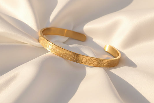 Bracelet jonc de luxe en acier inoxydable finition or, gravé de la calligraphie Ayatul Kursi, posé élégamment pour une mise en valeur esthétique et spirituelle.