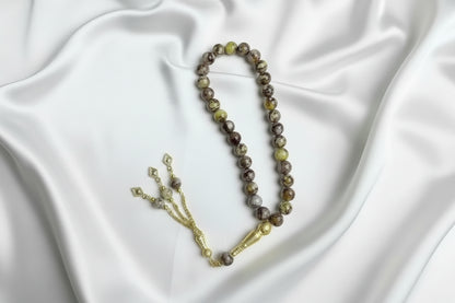 Tasbih de 33 perles de 10mm aux motifs marbrés jaune, marron et gris, avec séparateurs dorés et un grand pompon luxueux à chaînettes.