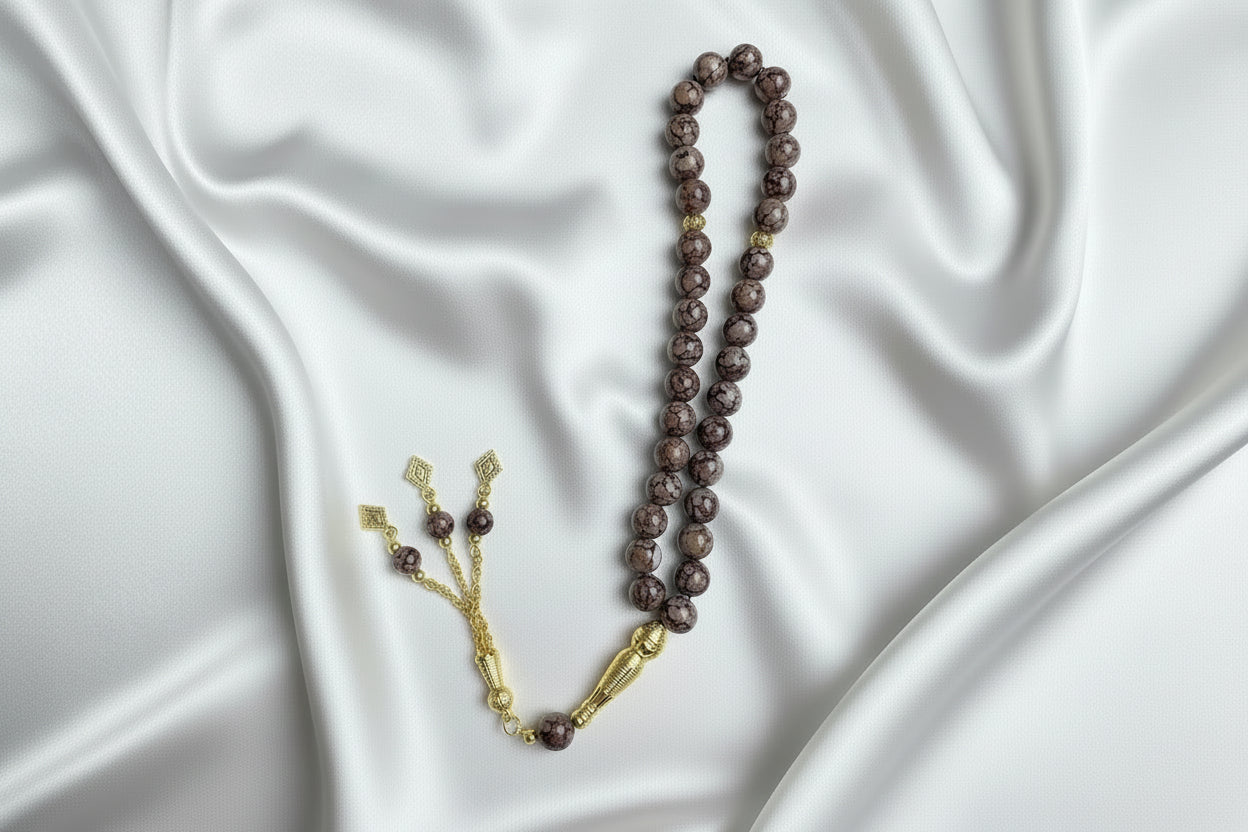 Tasbih de 33 perles de 10mm aux motifs marbrés violet foncé et blanc, avec finitions dorées, séparateurs ciselés et pompon à trois chaînettes dorées.