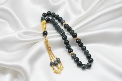 Tasbih de 33 perles de 10mm gris anthracite marbré avec des reflets brillants, séparateurs dorés ciselés et pompon luxueux doré avec pendentifs losanges.
