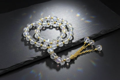 Tasbih haut de gamme en cristal transparent avec reflets irisés, perles facettées, détails en or incrustés de strass et pompon luxueux à chaînettes dorées.