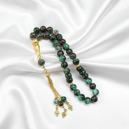 Tasbih de 33 perles marbrées vert et marron avec reflets brillants, séparateurs dorés ciselés et pompon luxueux avec trois pendentifs losanges en or.