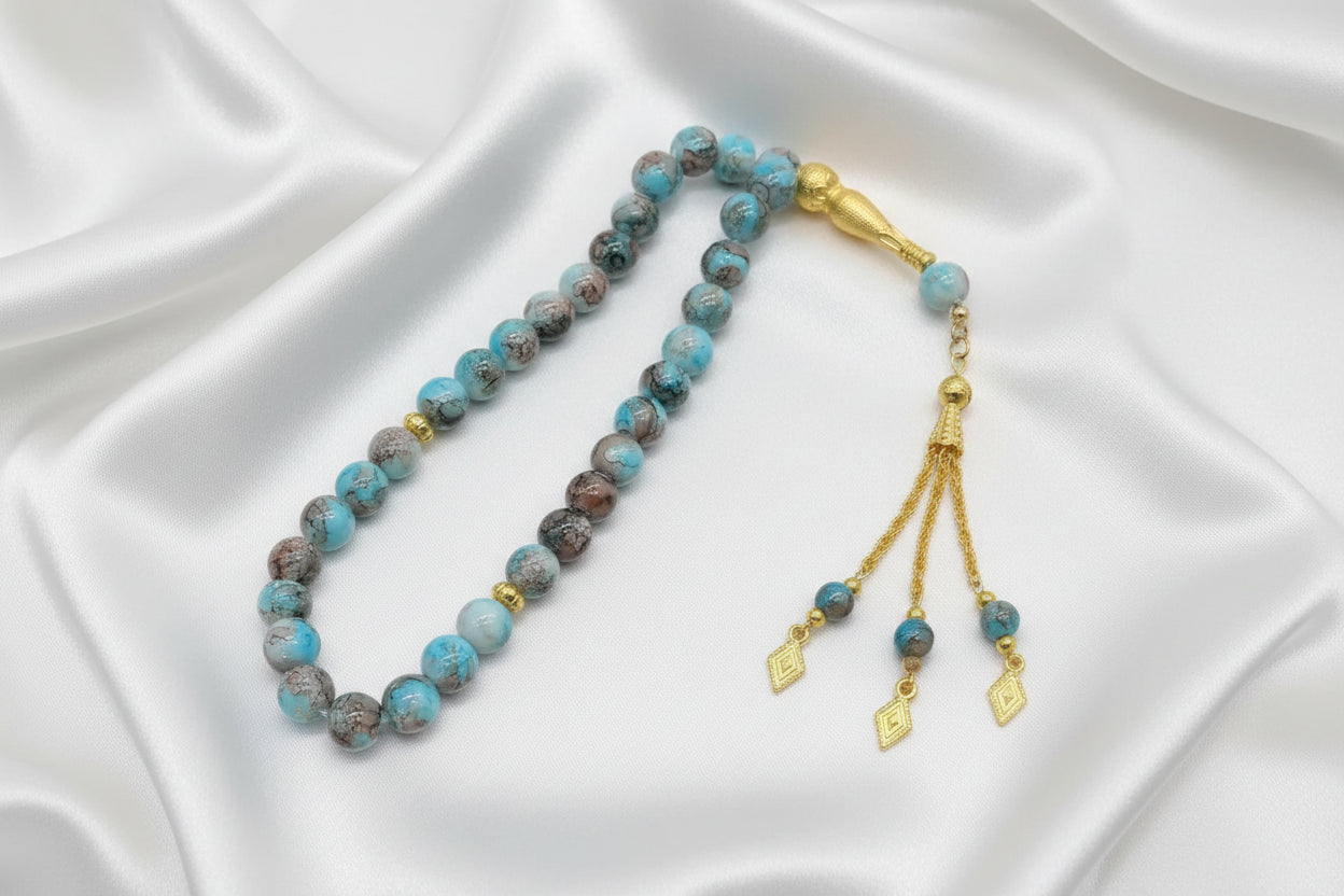 Tasbih de prière haut de gamme composé de 33 perles en verre facetté de 10mm. Finitions avec pompon doré artisanal et séparateurs dorés. Design religieux élégant pour homme et femme, disponible en plusieurs coloris.